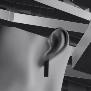 A greyscale image showing a close-up of a human ear wearing a rectangular earring, with modern, angular architectural structures in the blurred background—perfect for a curated concept store or stylish gift shop display. Gate21.ee