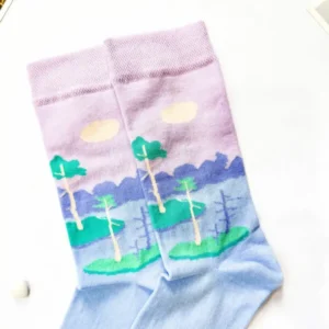 A pair of Eesti sokid – mine rappa! featuring a landscape design—trees, green grass, purple mountains, and a pink sky with clouds—laid flat on a white surface next to a New Rebels small rucksack. Gate21.ee