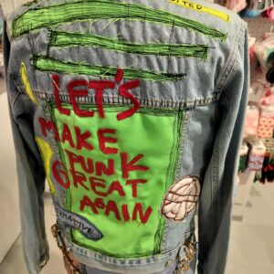 The mannequin showcases the Riivo Jacket, a denim piece with bright green patches and "LETS MAKE PUNK GREAT AGAIN" in red and black lettering, featuring sewn-on details&mdash;a bold example of Estonian design in a Tallinn shopping destination. Gate21.ee
