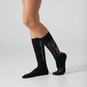 A person wears Basquiat Gem Spa - Athletic Black socks with colourful abstract designs and "Jean-Michel Basquiat" text, standing against a plain background—ideal for fans of unique concept shop style. Gate21.ee