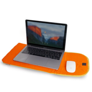 A silver laptop and white wireless mouse sit on a Puffy laptop sleeve 15´´- Orange, which features Estonian design and offers both protection and style inspired by Tallinn shopping trends. Gate21.ee