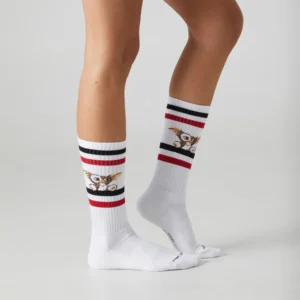 A person wearing Gremlins – Athletic white knee-high socks with red and black stripes and Gizmo on the sides, standing on a plain light surface—ideal for unique finds during your Tallinn shopping adventures. Gate21.ee