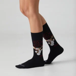 Someone wears Gremlins Warning – Regular black socks featuring Gizmo and the red text "Don't feed me after midnight." Set against a plain, light backdrop, these socks are a unique Tallinn shopping gift shop find. Gate21.ee