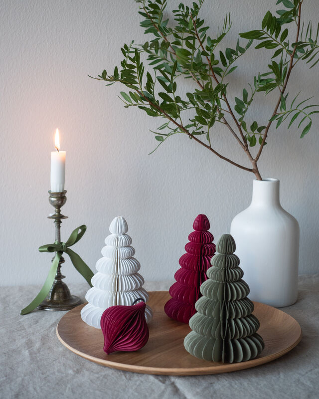 A curated display features a white candle in a metal holder, Paper Christmas Trees - 30cm - KÕIK in festive colours, and a white vase with green branches on a wooden tray—ideal inspiration for Tallinn shoppers or fans of Estonian design. Gate21.ee