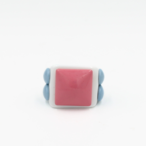 The Memphis - Ring showcases a large square pink stone set in a white band, accented by two rounded blue details on each side, displayed against a plain white background. Gate21.ee