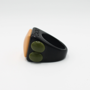 The Tommy - Ring features a chunky black band with an orange, rounded rectangle on top and two green ovals on the sides, highlighting Estonian design and originality, presented against a plain white background. Gate21.ee