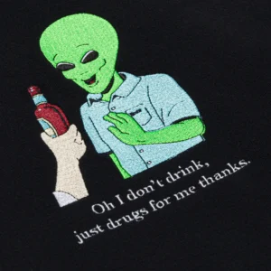 The I Don´t Drink hoodie - Black features a playful Estonian design of a smiling green alien in a blue shirt offering a bottle, with the text: Oh I don’t drink, just drugs for me thanks—perfect for unique gift shop finds. Gate21.ee