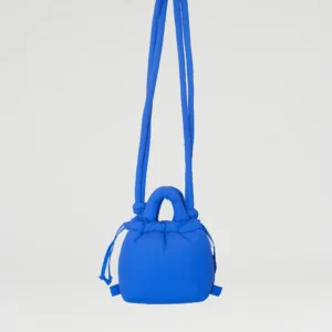 The Micro Ona Soft Bag - Cobalt Blue, a small handbag with padded handles and a long shoulder strap, floats against a plain light grey background—highlighting distinctive Estonian design. Gate21.ee