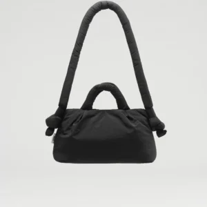 The Mini Ona Soft Bag - Black, featuring a large curved shoulder strap and two small handles, is displayed suspended against a plain light grey background—an elegant addition to any unique gift shop. Gate21.ee