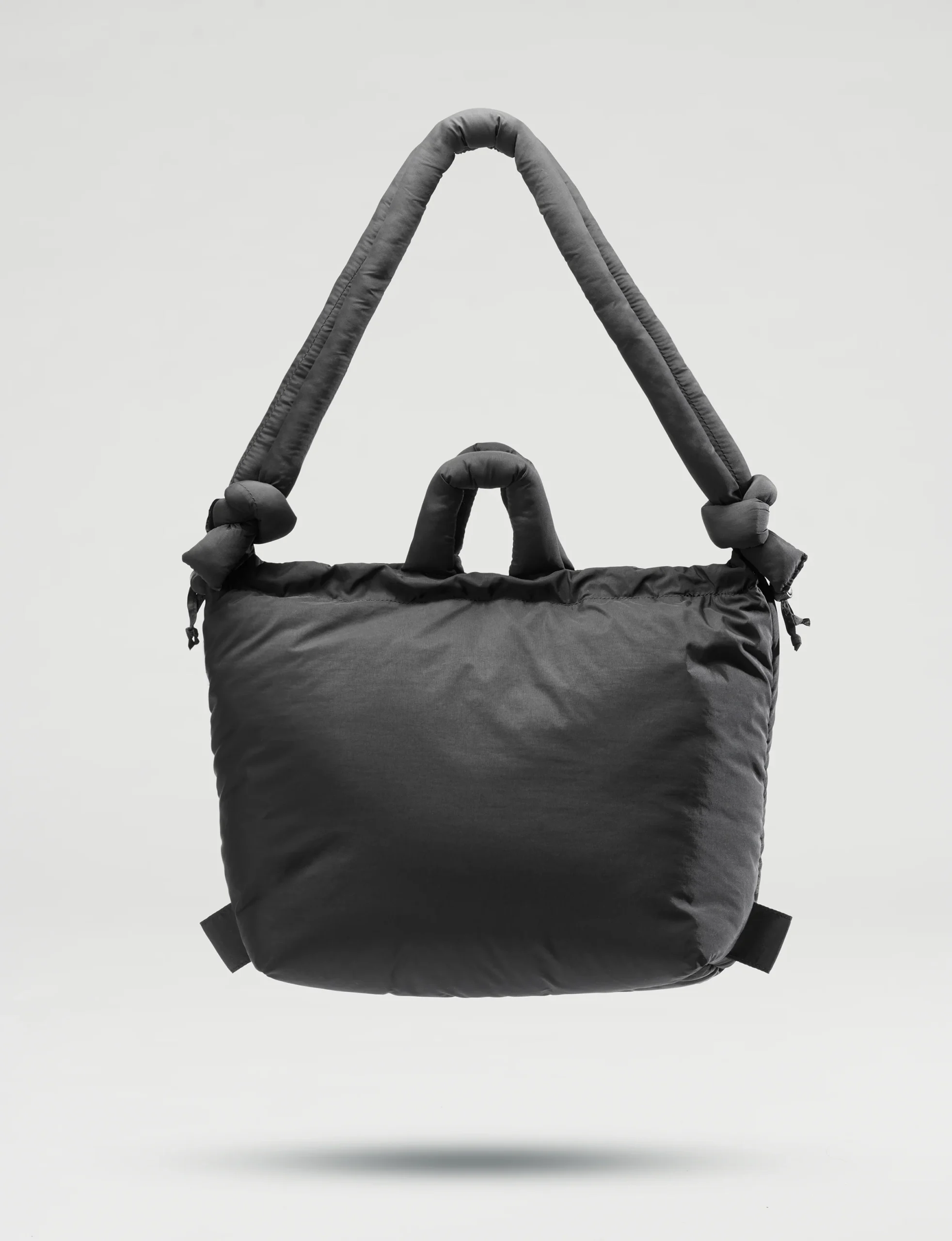 The Ona Soft Bag - Black is a padded tote with a thick, knotted shoulder strap and two short handles—a minimalist design ideal for Tallinn shopping or discovering unique ideas in your favourite gift shop. Gate21.ee