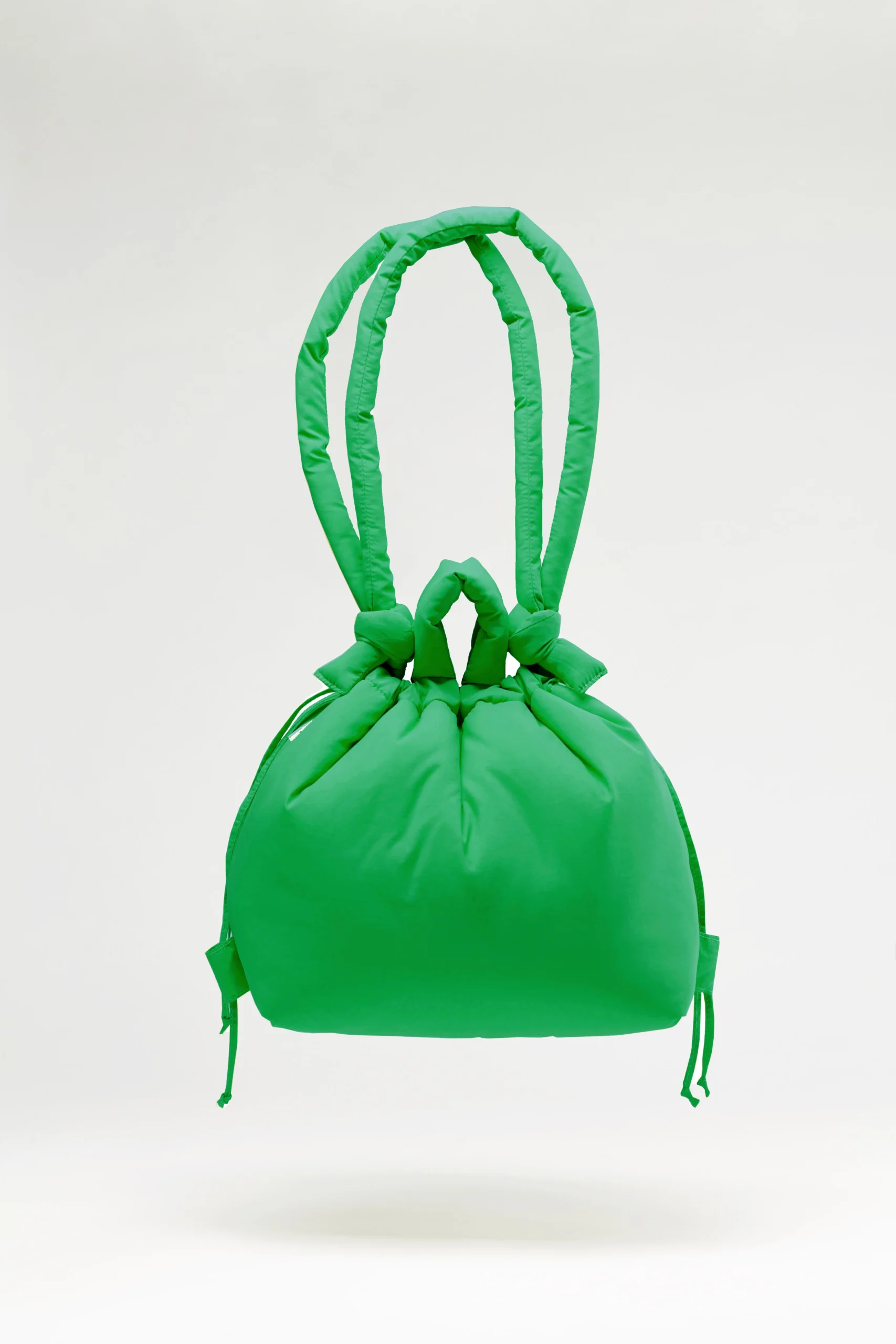The Ona Soft Bag - Green is a padded drawstring bag with two thick, looped handles. It features a smooth texture and gathered details, photographed against a plain light background for a curated look. Gate21.ee