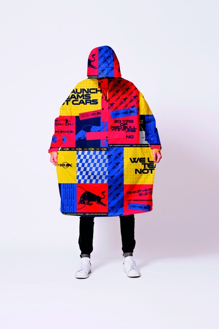 A person stands against a white background, wearing the Box Box – Special Edition hooded coat with bold, colourful Estonian-inspired graphics, plus black trousers and white trainers for a standout concept shop look. Gate21.ee
