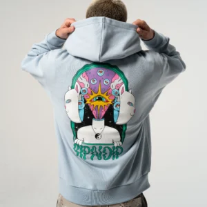 A person wearing the Mind Games hoodie - Powder Blue, featuring a vibrant surreal graphic with three white cat faces, an eye, psychedelic elements, stylised text at the bottom—showcasing bold Estonian design. Gate21.ee