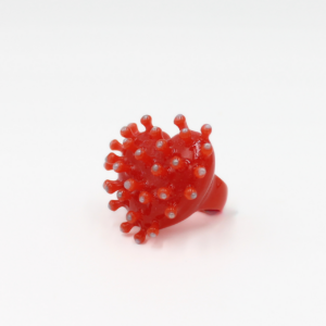 A “Virus - Ring” in bold red, designed by CACKO with a round, spiky form reminiscent of a virus or sea urchin, is displayed in the centre against a plain white background. Gate21.ee