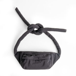 The Knotflex Pack - Black is a stylish waist bag featuring two long, padded straps tied in a knot and a front zipped pocket. Displayed on a white background, it’s perfect for creative projects or gift shop selections. Gate21.ee
