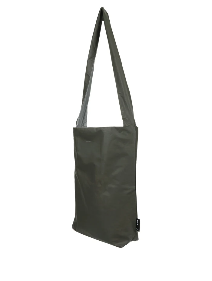 The Feel Good Bag - Olive Night by Tinne+mia is a plain, olive-green tote with a long strap and rectangular shape, photographed against a white background. A small black tag is attached to the lower side of the bag. Gate21.ee