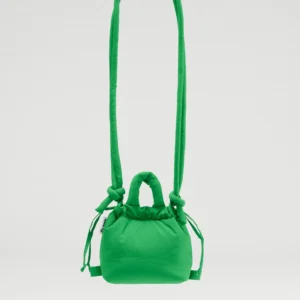 The Micro Ona Soft Bag - Green is a compact, vibrant handbag featuring a long padded strap and knotted accents. This curated piece of Estonian design is displayed suspended against a plain white background. Gate21.ee