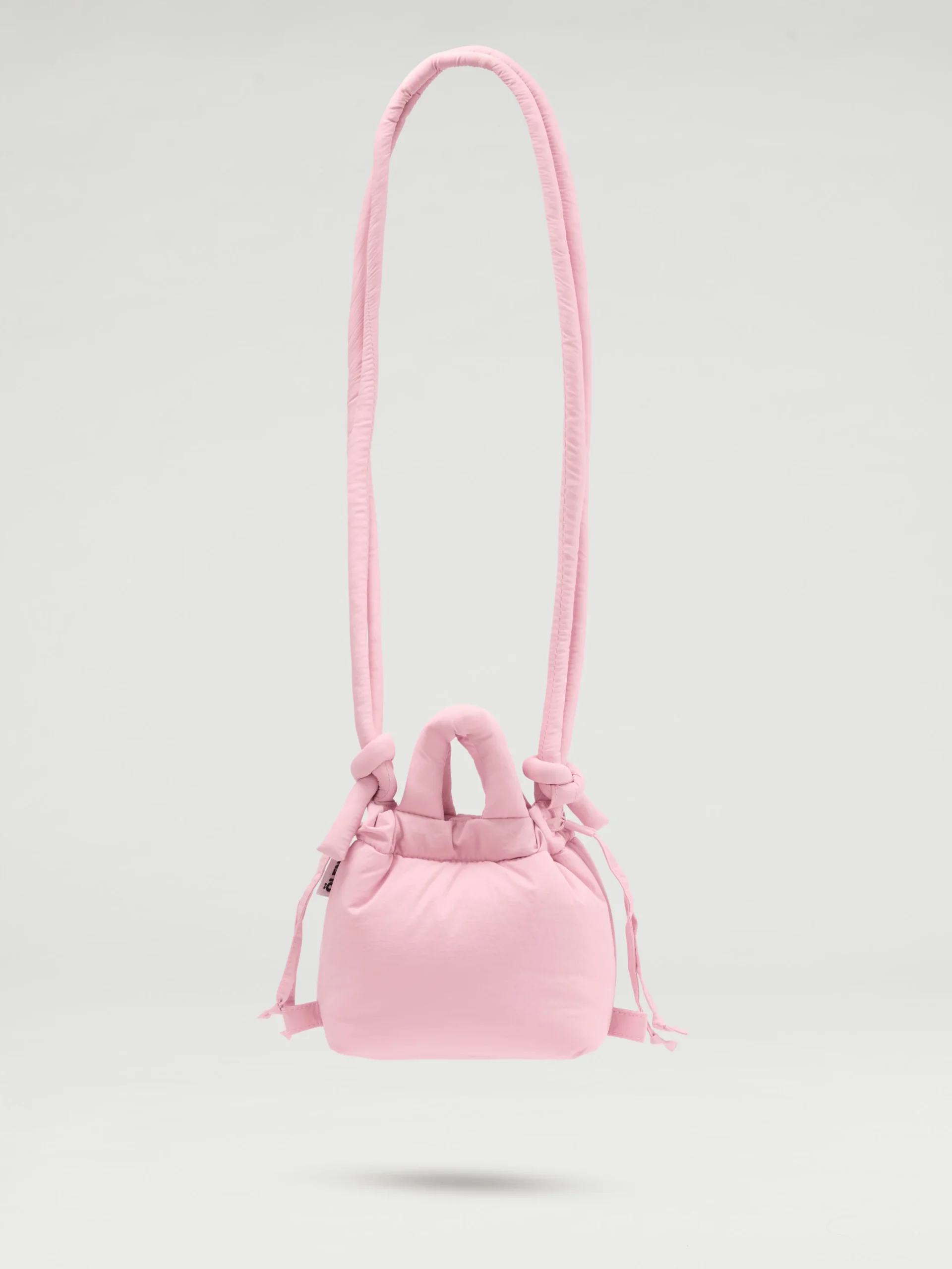 The Micro Ona Soft Bag in pale pink features a padded texture, two short handles, and a thick padded shoulder strap—ideal for Tallinn shopping—displayed against a plain light grey background. Gate21.ee