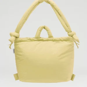 The Ona Soft Bag - Lime is a pale yellow padded tote featuring short handles and a long, thick cushioned strap knotted at both ends, inspired by unique Estonian design and set against a plain light background. Gate21.ee