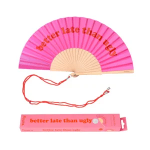 The "Better late than ugly!" fan is a pink folding hand fan with red lettering, a red strap, and a matching pink box—stylish finds from a curated concept store for your next Tallinn shopping adventure. Gate21.ee