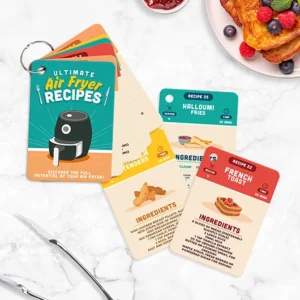 A set of "Air Fryer - 100 Recipe Cards" is displayed on a white marble surface. The top card features 'Ultimate Air Fryer Recipes' with ideas like halloumi fries and eggy bread. Nearby, berries and eggy bread complete the scene. Gate21.ee