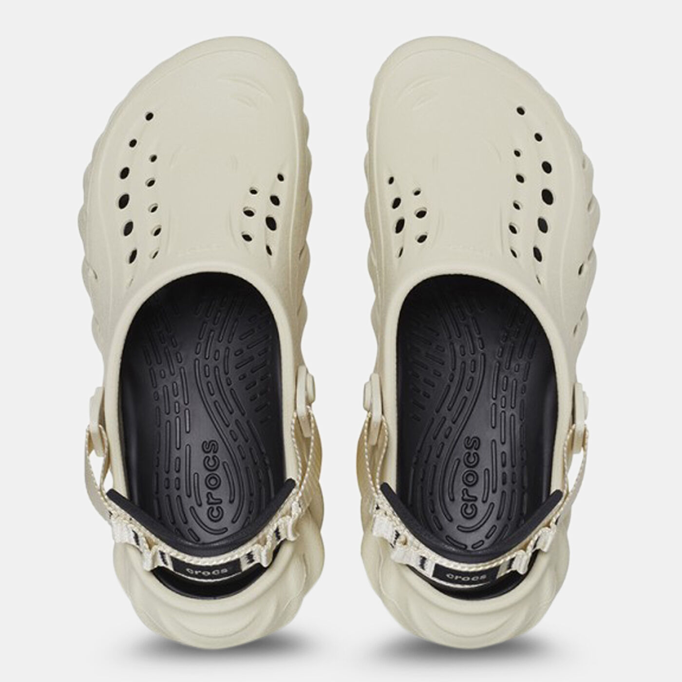 The Crocs™ Echo Clog in Bone/Black features slip-on comfort, black insoles, adjustable heel straps, ventilation holes, and a textured sole—shown from above on a white background as an example of curated Estonian design. Gate21.ee