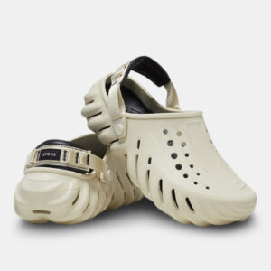 A pair of Crocs™ Echo Clog in Bone/Black, featuring black adjustable heel straps, ventilation holes on top, and a wavy textured sole. One shoe stands upright whilst the other is tilted on its side. Estonian design inspired. Gate21.ee