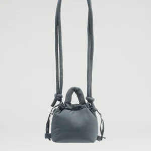 The Micro Ona Soft Bag - Coal is a compact, grey padded crossbody with a long strap, short handles, side drawstrings, and a minimalist look—perfect for concept shops—shown against a plain white background. Gate21.ee
