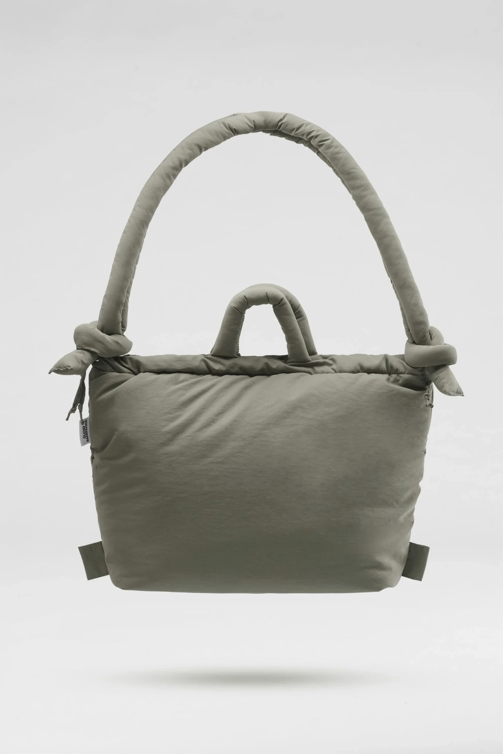 The Ona Soft Bag - Sage is a soft, light grey padded tote with two handles—one short, one long and knotted—highlighting Estonian design. Ideal for Tallinn shopping or visiting your favourite concept store. Shown on a plain white background. Gate21.ee