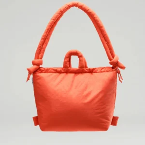 The Ona Soft Bag - Coral is a vibrant orange, padded handbag with a large rounded and smaller top handle, exemplifying curated Estonian design against a plain light grey background. Gate21.ee