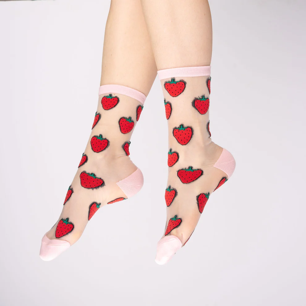 A pair of legs models the Strawberry - Transparent Socks, featuring sheer ankle material with pink heels, toes, and cuffs plus a red strawberry pattern. The background is plain white. Gate21.ee