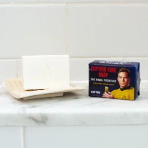 A white bar of Captain Kirk - Soap with the Star Trek insignia rests on a dish beside a box labelled "Captain Kirk Soap: The Final Frontier" with Federation herbal scent, by the Unemployed Philosophers Guild, featuring Captain Kirk’s image. Gate21.ee