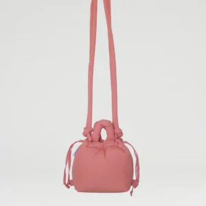 The Micro Ona Soft Bag in Soft Peach, featuring a knotted handle and long shoulder straps, is suspended against a plain white background—an elegant bag ideal for concept shops or gift shops. Gate21.ee