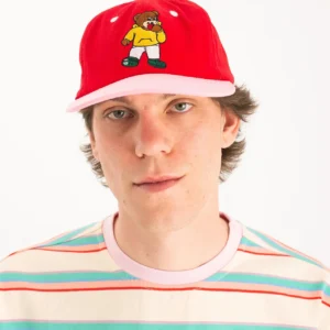 Wearing the Teddyarchy Cap—a red and pink hat with a cartoon bear—this person stands against a plain white background, highlighting creative ideas from an Estonian design gift shop. Gate21.ee