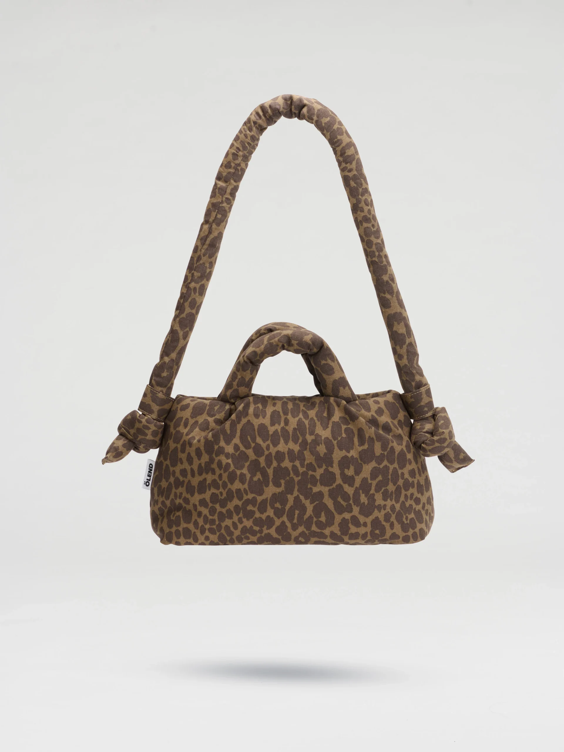 The Mini Ona Soft Bag - Leopard is a brown handbag with a leopard print, two handles, and two knots at the base of the longer handle, shown against a plain white background. Gate21.ee