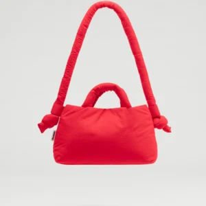 The Mini Ona Soft Bag - Red is a bright padded handbag with short handles and a long, knotted strap, highlighting unique Estonian design, displayed against a plain light background. Gate21.ee