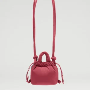 The Micro Ona Soft Bag - Cherry Red, a small square-shaped handbag with a plush finish, padded handle, long shoulder strap, and side drawstrings, showcases curated Estonian design against a plain white background. Gate21.ee