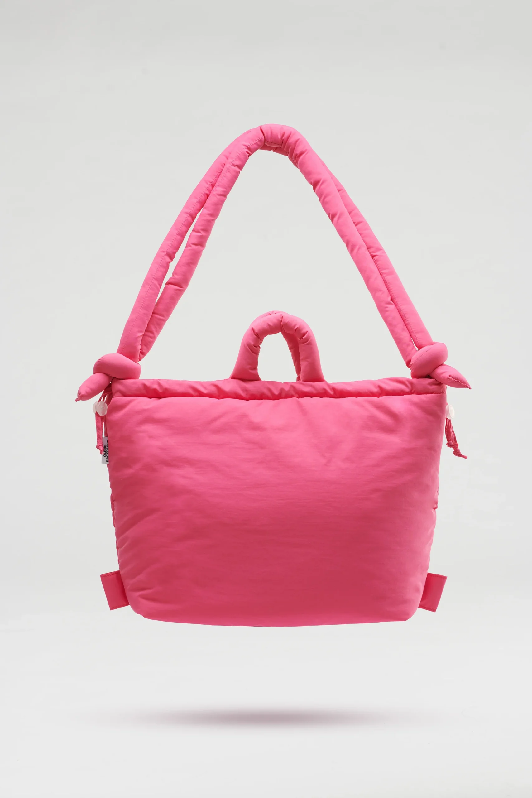 The Ona Soft Bag - Pink is a bright pink padded tote with two thick shoulder straps and knot details, showcasing Estonian design against a plain light grey background. Gate21.ee