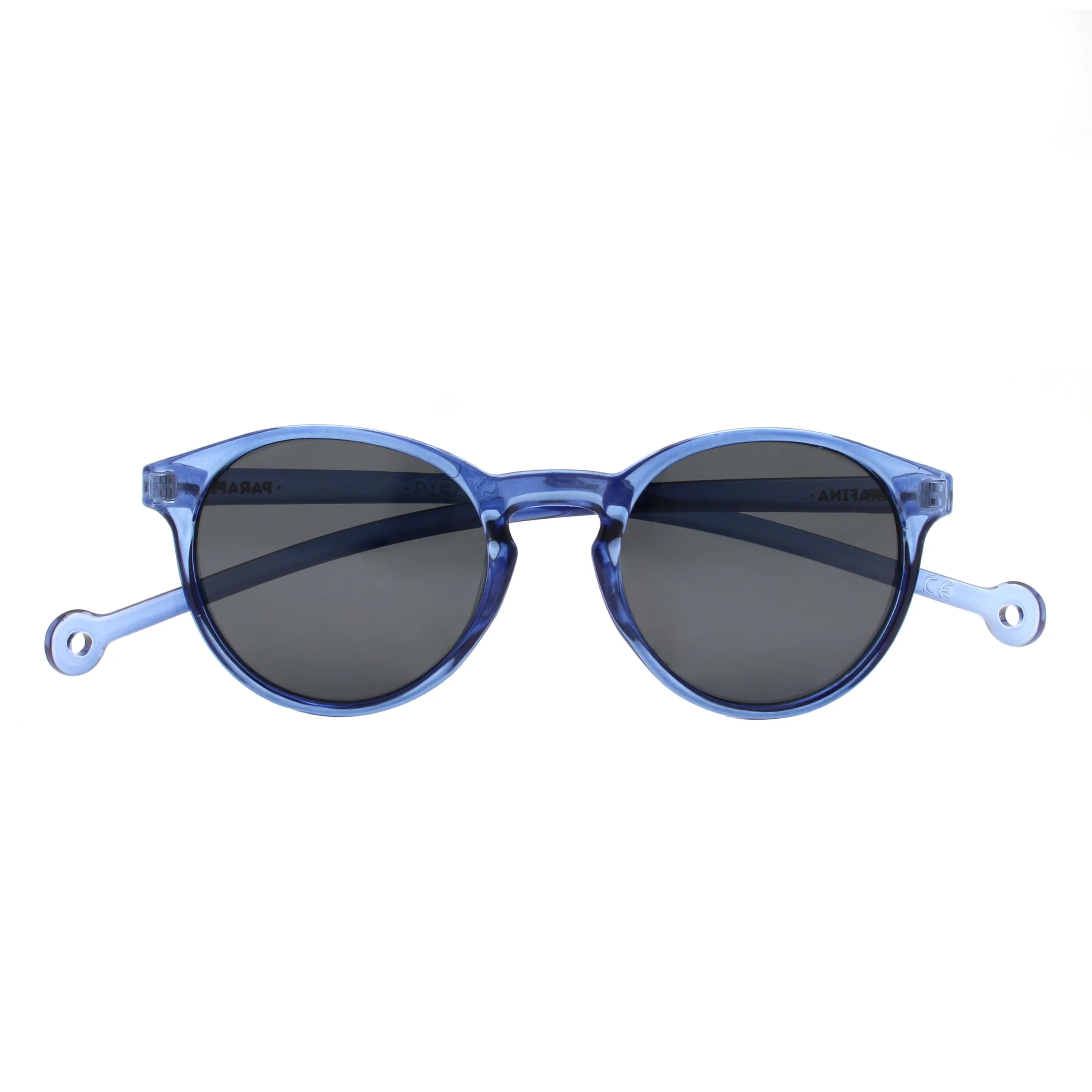 The "Isla" Blue Sunglasses feature round, translucent blue frames and dark lenses, accented by small circular holes near the temple ends. Showcasing Estonian design, they're a standout choice against a white background for any gift shop. Gate21.ee