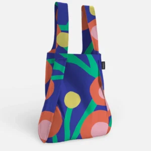 The Blossom – Special Edition reusable tote stands upright, showcasing bold orange, yellow, and pink circles with green curves on a dark blue background—a curated choice for gift shops and concept stores. Gate21.ee
