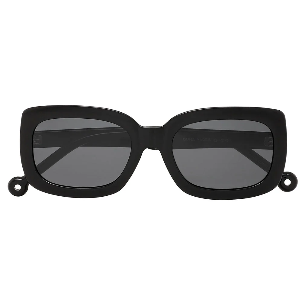 The "Duna" Black Sunglasses feature a rectangular shape with thick frames, dark lenses, and a small circular loop on each temple—perfect for bringing unique style to your concept store or gift shop selection. Gate21.ee