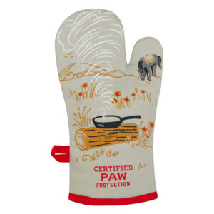The Boss Kitty Oven Mitt is a beige BlueQ mitt with red trim, featuring a printed design of a frying pan on a log with smoke, wildflowers, mountains, and a dog. The text at the bottom reads “CERTIFIED PAW PROTECTION.”. Gate21.ee