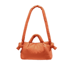 The Mini Ona Soft Bag - Oxide is a soft, rectangular orange bag with two padded handles (one short, one long) and decorative fabric knots on each side, shown against a white background—perfect for stylish shopping or as a chic present. Gate21.ee