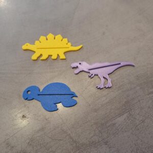 The Lucky Laika Toothpaste holder - K&Otilde;IK features colourful, whimsical designs&mdash;like a yellow stegosaurus, purple T. rex, and blue turtle&mdash;making it a fun, unique gift shop addition. Gate21.ee