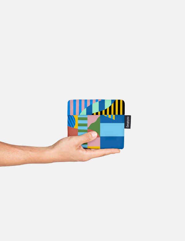 A hand displays the Landscape - Special Edition wallet, showcasing vibrant geometric patterns in blue, green, yellow, pink, and black with a small black side tag against a white background&mdash;a unique idea for Tallinn shopping. Gate21.ee
