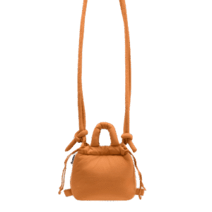 The Micro Ona Soft Bag - Oxide is a compact orange rectangular crossbody with a long strap, side drawstrings, and knot details—an eye-catching example of Estonian design, perfect for gifting and shown on a white background. Gate21.ee