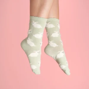 A pair of feet in Rabbits - Grey Cotton Socks, featuring a cute bunny pattern, shown against a pink background—ideal for fans of Estonian design and unique concept shop finds. Gate21.ee