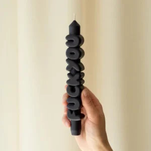 A hand holds the F*ck You 3D Candle - Black, featuring bold raised lettering and showcasing striking Estonian design against a neutral backdrop. Gate21.ee
