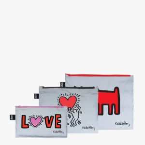 The Keith Haring 3x Zip Pockets - LOQI REFLECTIVE set includes three grey zippered pouches featuring Keith Haring-inspired designs: one with the word LOVE, one showcasing a figure holding a heart, and one with a red dog. Each pouch is accented with reflective details and contrasting zip colours for added style, and comes equipped with secure zip pockets to keep your essentials safe. Gate21.ee
