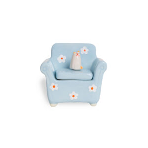 The Blue Chair - Jewellery Box is a small ceramic piece shaped like a blue armchair with white and orange flowers, featuring a white cat on the seat. Showcasing Estonian design, it’s ideal for adding charm to your home or gift shop display. Plain white background. Gate21.ee
